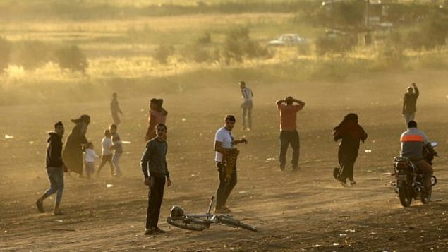 متظاهرون فلسطينيون يهربون من الغاز المسيل للدموع الذي أطلقته القوات الإسرائيلية خلال احتجاجات عند الحدود مع إسرائيل، شرقي مدينة غزة في قطاع غزة، 31 مارس، 2018. (AFP PHOTO / MAHMUD HAMS)