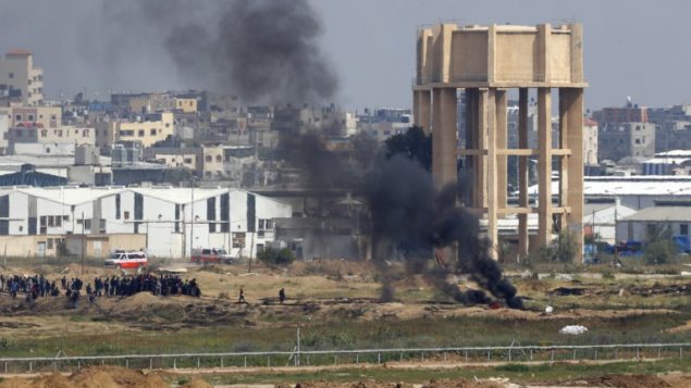 صورة التقطت من كيبوتس ناحال عوز الإسرائيلي مقابل الحدود بين اسرائيل وغزة، تظهر متظاهرين فلسطينيين ودخان اسود يتصاعد في الطرف الثاني من الحدود، 6 ابريل 2018 (AFP PHOTO / Jack GUEZ)
