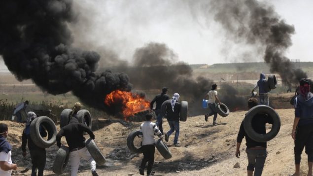 فلسطينيون يشعلون الاطارات للحماية من القناصين الإسرائيليين خلال اشتباكات عند الحدود بين غزة واسرائيل، 6 ابريل 2018 (MAHMUD HAMS / AFP)