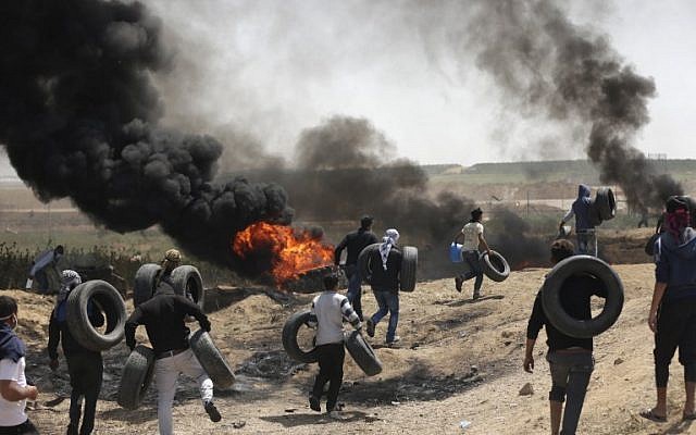 فلسطينيون يشعلون الاطارات للحماية من القناصين الإسرائيليين خلال اشتباكات عند الحدود بين غزة واسرائيل، 6 ابريل 2018 (MAHMUD HAMS / AFP)