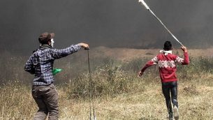 متظاهرون فلسطينيون يستخدمون المقاليع لرشق القوات الإسرائيلية بالحجارة خلال مواجهات عند حدود غزة مع إسرائيل في جنوب قطاع غزة، 6 أبريل، 2018. (AFP PHOTO / SAID KHATIB)