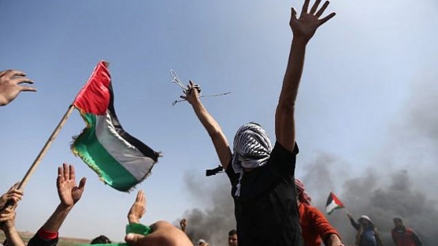 متظاهرون فلسطينيون يلوحون بعلمهم الوطني ويرددون هتافات ضد قوات الأمن الإسرائيلية خلال احتجاج على الحدود بين إسرائيل وغزة في شمال قطاع غزة في 6 أبريل / نيسان 2018. (AFP/Mohammed Abed)
