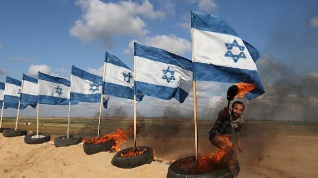 متظاهر فلسطيني يستعد لحرق أعلام إسرائيلية في 10 أبريل، 2018 في موقع الاحتجاجات بالقرب من الحدود بين غزة وإسرائيل شرق جباليا في شمال قطاع غزة. (AFP PHOTO / Mohammed ABED)