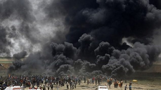 فلسطينيون يحرقون إطارات في السياج الحدودي مع إسرائيل،  شرق جباليا في وسط مدينة غزة، خلال مظاهرة في 13 أبريل، 2018. (AFP PHOTO / MOHAMMED ABED)
