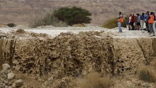 اسرائيليون يراقبون مياه جرف سدت طريق رئيسي بالقرب من البحر الميت، في اعقاب امطار عزيرة في الجبال المحيطة، 25 ابريل 2018 (AFP PHOTO / MENAHEM KAHANA)
