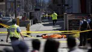 TORONTO, ON - APRIL 23: A tarp lays on top of a body on Yonge St. at Finch Ave. after a van plowed into pedestrians on April 23, 2018 in Toronto, Canada. A suspect is in custody after a white van collided with multiple pedestrians.   Cole Burston/Getty Images/AFP