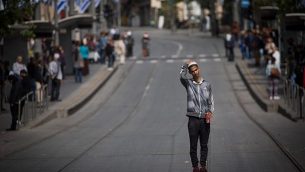 أشخاص يقفون بصمت في شارع يافا في وسط مدينة القدس مع سماع صفارات الإنذار لمدة دقيقتين في جميع أنحاء إسرائيل لإحياء ذكرى المحرقة في 12 أبريل، 2018. (Yonatan Sindel/Flash90)