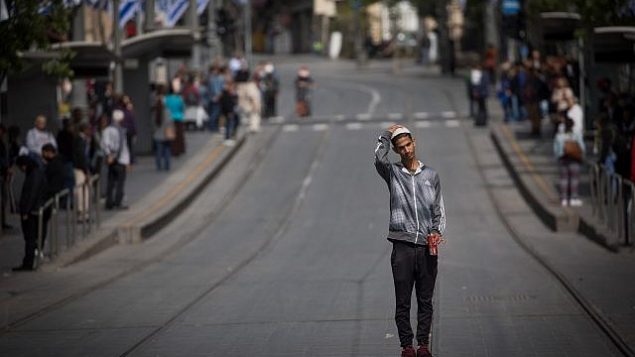 أشخاص يقفون بصمت في شارع يافا في وسط مدينة القدس مع سماع صفارات الإنذار لمدة دقيقتين في جميع أنحاء إسرائيل لإحياء ذكرى المحرقة في 12 أبريل، 2018. (Yonatan Sindel/Flash90)