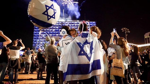 أشخاص يشاهدون غرض الألعاب النارية احتفالا بيوم استقلال إسرائيل ال70 في تل أبيب، 18  أبريل، 2018. (Miriam Alster/Flash90)