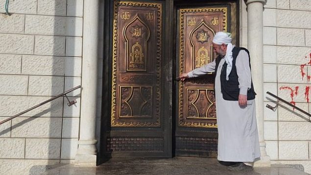 إمام مسجد في قرية عقربا الفلسطينية في شمال الضفة الغربية يتفقد الأضرار التي لحقت بالمسجد جراء هجوم ’دفع ثمن’ وقع في 13 أبريل، 2018. (Zacharia Sadeh/Rabbis for Human Rights)