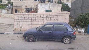 سيارة تم تمزيق اطاراتها امام حائط تم تخريبه بعبارة باللغة العبرية في قرية دير عمار الفلسطينية في الضفة الغربية، 25 ابريل 2018 (Yesh Din)