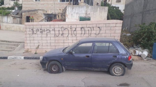 سيارة تم تمزيق اطاراتها امام حائط تم تخريبه بعبارة باللغة العبرية في قرية دير عمار الفلسطينية في الضفة الغربية، 25 ابريل 2018 (Yesh Din)