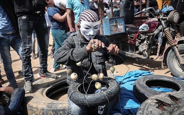 رجل فلسطيني مقنع يتهيأ للتظاهر مع بصل، الذي يهدف تخفيف تأثير الغاز المسيل للدموع بالقرب من خان يونس، شرقي مدينة غزة، 6 ابريل 2018 (SAID KHATIB / AFP)