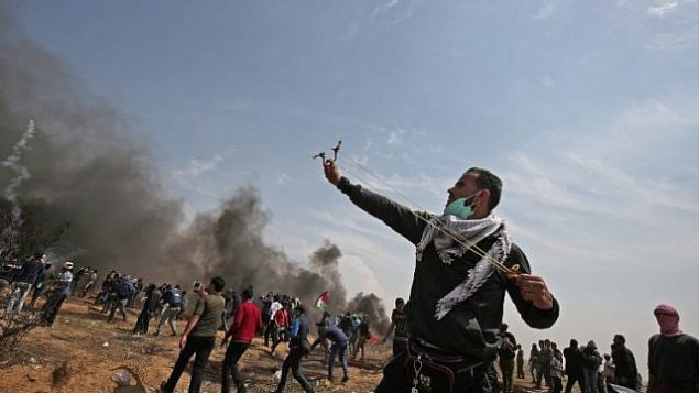 متظاهر  فلسطيني  يستخدم   مقلاعا لإلقاء الحجارة على الجنود الإسرائيليين بالقرب من مدينة خان يونس، في جنوب قطا ع غزة، خلال يوم الجمعة الخامس على التوالي من المظاهرات الحاشدة والمواجهات عند الحدو بين غزة وإسرائيل في 27 أبريل، 2018.  (AFP Photo/Said Khatib)