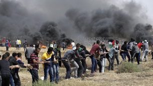 فلسطينيون يحاولون إسقاط جزء من السياج الحدودي بين إسرائيل وغزة شرق جباليا في شمال قطاع غزة، خلال خامس يوم على التوالي من التظاهرات على طول الحدود بين غزة وإسرائيل، في 27 أبريل، 2018. (AFP Photo/Mahmud Hams)