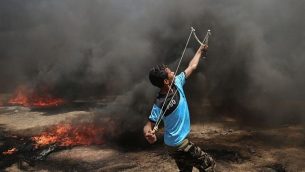 شاب فلسطيني يستخدم المقلاع خلال مواجهات مع القوات الإسرائيلية بالقرب من حدود غزة وإسرائيل شرقي مدينة خان يونس، 14 مايو، 2018. (AFP PHOTO / SAID KHATIB)