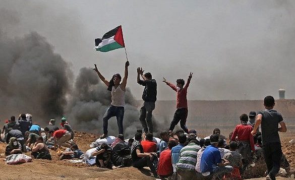 فلسطينيون يلوحون بعلمهم خلال مظاهرات بالقرب من الحدود بين اسرائيل وقطاع غزة، 14 مايو 2018 (AFP PHOTO / MOHAMMED ABED)
