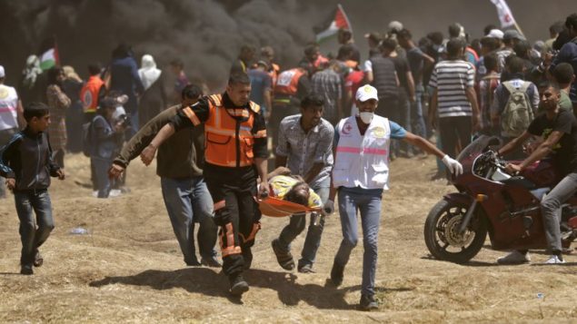 فلسطينيون يحملون متظاهراً أصيب خلال اشتباكات مع الجيش الإسرائيلي بالقرب من الحدود بين قطاع غزة وإسرائيل  14 مايو / أيار 2018 يوم تدشين السفارة الأمريكية في القدس MAHMUD HAMS / AFP