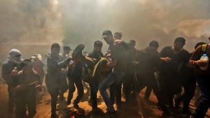 فلسطينيون يحملون متظاهرًا جريحًا خلال مواجهات مع القوات الإسرائيلية بالقرب من الحدود بين قطاع غزة وإسرائيل شرق مدينة غزة يوم 14 مايو 2018. (MAHMUD HAMS / AFP)