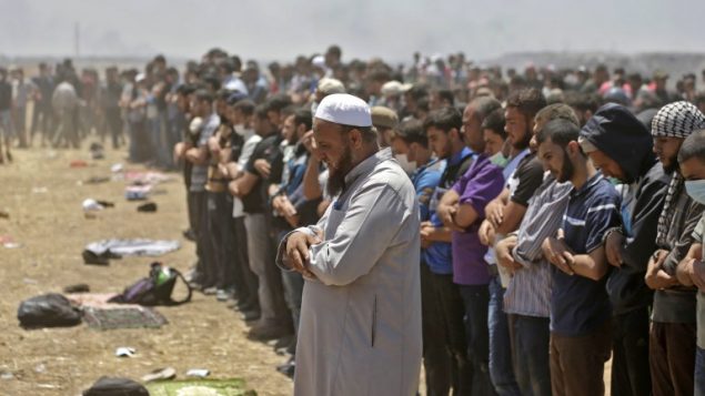 صلاة قبل المظاهرة والاشتباكات بين فلسطينيين والجيش الإسرائيلي بالقرب من الحدود بين قطاع غزة وإسرائيل  14 مايو / أيار 2018 يوم تدشين السفارة الأمريكية في القدس MAHMUD HAMS / AFP