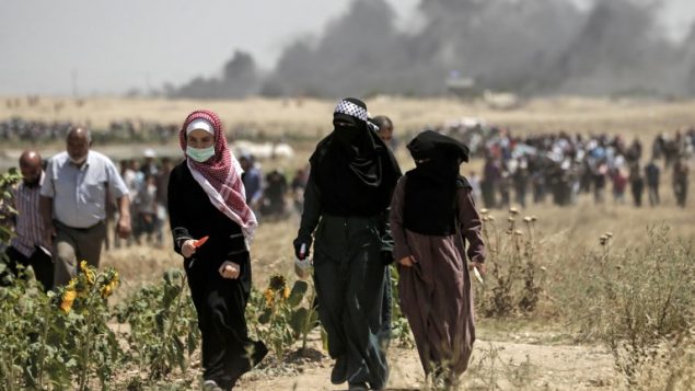 نساء فلسطينيات يشاركن في المظاهرة خلال اشتباكات بين فلسطينيين والجيش الإسرائيلي بالقرب من الحدود بين قطاع غزة وإسرائيل  14 مايو / أيار 2018 يوم تدشين السفارة الأمريكية في القدس MAHMUD HAMS / AFP