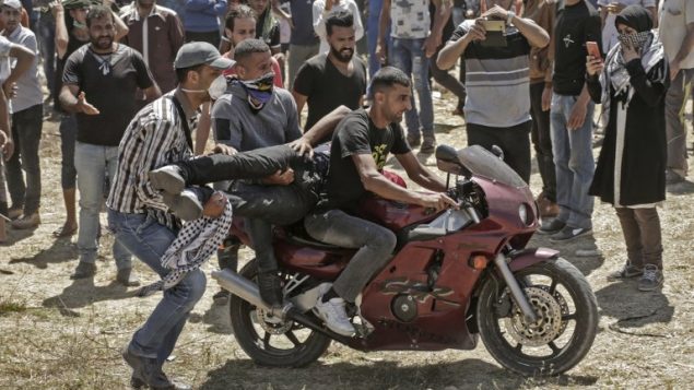 فلسطينيون يحملون متظاهراً أصيب خلال اشتباكات مع الجيش الإسرائيلي بالقرب من الحدود بين قطاع غزة وإسرائيل  14 مايو / أيار 2018 يوم تدشين السفارة الأمريكية في القدس MAHMUD HAMS / AFP