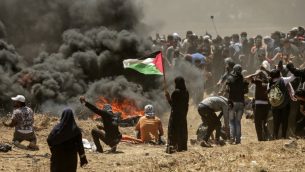 امرأة من غزة تحمل العلم الفلسطيني امام  اشتباكات بين فلسطينيين والجيش الإسرائيلي بالقرب من الحدود بين قطاع غزة وإسرائيل  14 مايو / أيار 2018 يوم تدشين السفارة الأمريكية في القدس MAHMUD HAMS / AFP