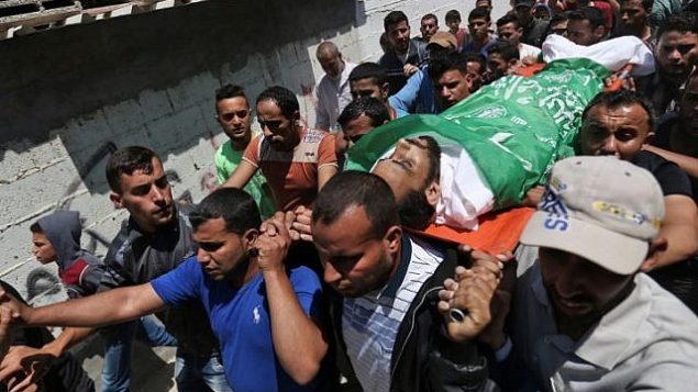 المشيعون يحملون جثمان الشاب الفلسطيني محمد دويدر (27 عاما)، الذي قُتل خلال مواجهات على الحدود بين غزة وإسرائيل في اليوم السابق، خلال جنازته في مخيم النصيرات في قطاع غزة، 15 مايو، 2018.  (AFP PHOTO / MOHAMMED ABED)
