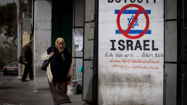امرأة فلسطينية تمر من أمام  رسم على جدار يدعو إلى مقاطعة إسرائيل في أحد شوارع مدينة بيت لحم في الضفة الغربية، 11 فبراير، 2015. (Miriam Alster/Flash 90)