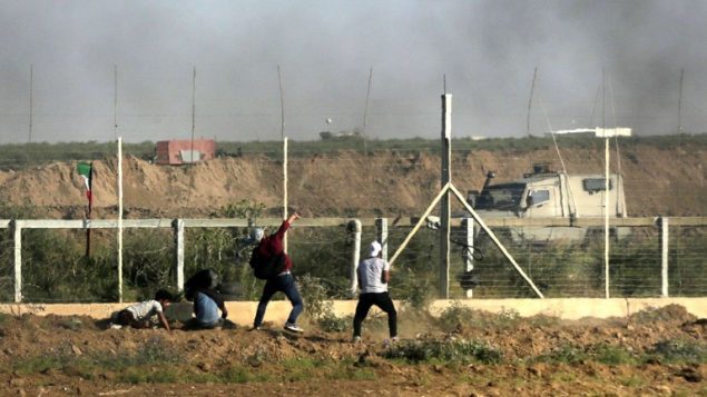 رجل فلسطيني يرمي حجرا باتجاه القوات الإسرائيلية خلال مظاهرة عند حدود غزة، 1 يونيو 2018 (AFP/ Mahmud Hams)