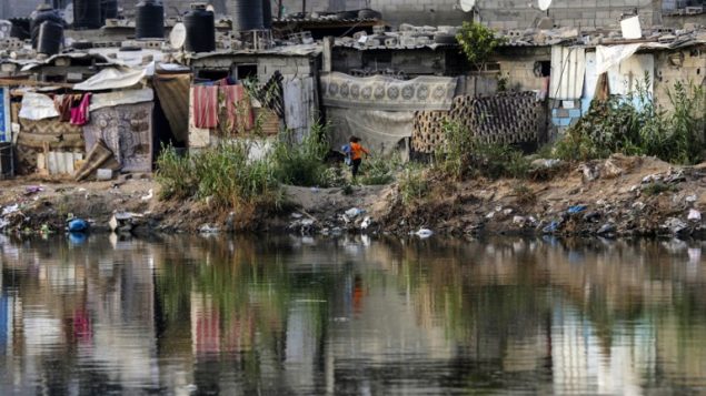 اكواخ بالقرب من بركة مياه صرف في حي فقير في مدينة غزة، 1 يونيو 2018 (AFP/Mahmud Hams)