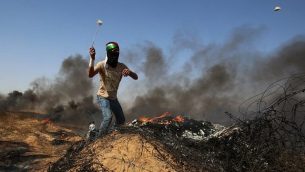 شاب فلسطيني يستخدم مقلاع لإلقاء الحجارة على القوات الإسرائيلية خلال اشتباكات قرب الحدود مع إسرائيل، شرق خان يونس في جنوب قطاع غزة في 8 يونيو  2018. (Said Khatib/AFP)