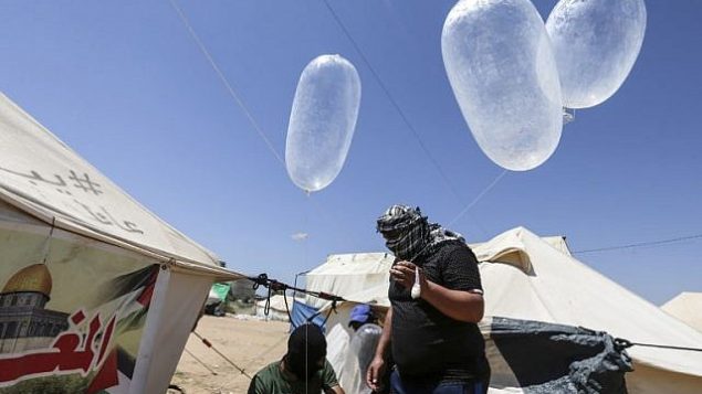 محتجون فلسطينيون يعدون طائرات ورقية محملة بمواد حارقة لإطلاقها باتجاه إسرائيل، ، عند حدود غزة إسرائيل في البريج، وسط قطاع غزة، 14 يونيو، 2018. (AFP/Mahmud Hams) محتجون فلسطينيون يعدون طائرات ورقية محملة بمواد حارقة لإطلاقها باتجاه إسرائيل، ، عند حدود غزة إسرائيل في البريج، وسط قطاع غزة، 14 يونيو، 2018. (AFP/Mahmud Hams)