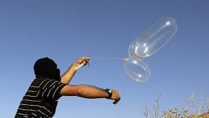 رجل فلسطيني ملثم يطلق بالونات محملة بمزاد مشتعلة باتجاه اسرائيل، شرقي رفح، جنوب قطاع غزة، 17 يونيو 2018 (AFP PHOTO / SAID KHATIB)