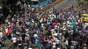 متظاهرون إيرانيون يرفعون شعارات خلال مظاهرة بوسط طهران في 25 يونيو عام 2018. نظم التجار في سوق البازار الكبير بالعاصمة الإيرانية إضرابا نادرا احتجاجا على انهيار الريال في سوق الصرف الأجنبي مع خروج المتظاهرين أيضا إلى الشوارع. (ATTA KENARE / AFP)