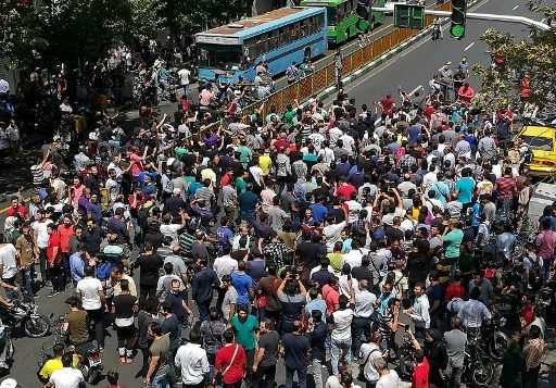 متظاهرون إيرانيون يرفعون شعارات خلال مظاهرة بوسط طهران في 25 يونيو عام 2018. نظم التجار في سوق البازار الكبير بالعاصمة الإيرانية إضرابا نادرا احتجاجا على انهيار الريال في سوق الصرف الأجنبي مع خروج المتظاهرين أيضا إلى الشوارع. (ATTA KENARE / AFP)