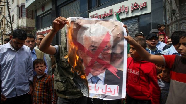متظاهرون في غزة يحملون صورة مشطوبة لرئيس السلطة الفلسطينية محمود عباس الله في خان يونس، 14 ابريل 2017 (Abed Rahim Khatib/Flash90)