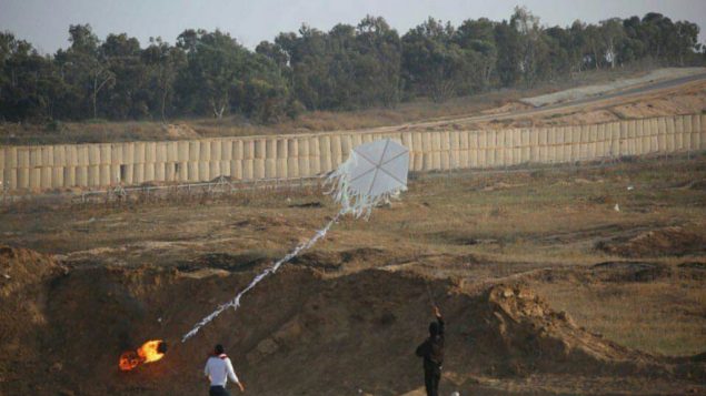 فلسطينيان يساعدان في إطلاق "طائرة ورقية" من قطاع غزة إلى الأراضي الإسرائيلية خلال مظاهرات حاشدة على طول السياج الحدودي ​​في 8 يونيو / حزيران 2018. (الجيش الإسرائيلي)
