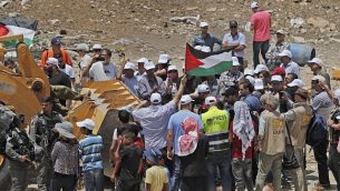يرفع المتظاهرون الأعلام الفلسطينية وهم يحاولون منع جرافات من فتح طريق وصول إلى قرية الخان الأحمر البدوية في الضفة الغربية في 4 يوليو 2018. (AFP Photo/Ahmad Gharabli)