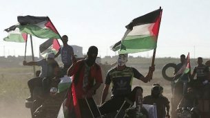 متظاهر فلسطيني يرتدي قناع غاي فوكس ويحمل علمه الفلسطيني خلال مظاهرة على طول الحدود بين إسرائيل وقطاع غزة، شرق مدينة غزة في 27 يوليو، 2018. (AFP PHOTO / MAHMUD HAMS)