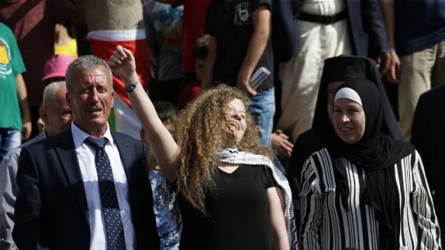 الناشطة الفلسطينية عهد التميمي (وسط الصورة) تقف بين والدها (وسط-يسار) ووالدتها (وسط-يمين) خلال مؤتمر صحفي في قرية النبي صالح الواقعة في الضفة الغربية في 29 يوليو، 2018، بعد إطلاق سراحها من السجن الإسرائيلي حيث قضت عقوبة بالسجن لمدة 8 أشهر. (/ AFP PHOTO / ABBAS MOMANI)