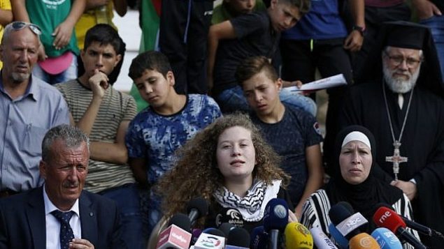 الناشطة الفلطسينية عهد التميمي (وسط الصورة) تجلس بين والدها باسم ووالدتها ناريمان خلال مؤتمر صحفي في قرية النبي صالح في الضفة الغربية، 29 يوليو، 2018. (AFP/ABBAS MOMANI)