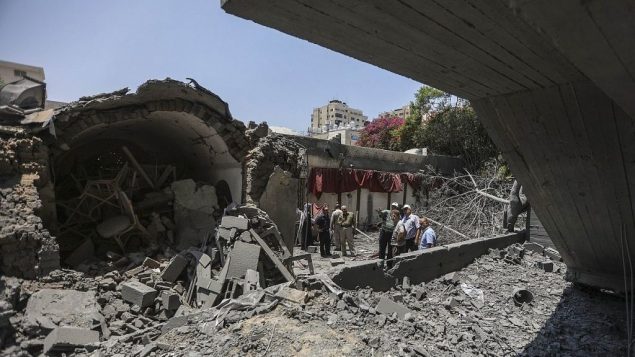 صبيان فلسطينيون يسيرون عبر حطام مبنى تضرر في غارات جوية إسرائيلية في مدينة غزة، 15 يوليو، 2018. (Wissam Nassar/Flash90)