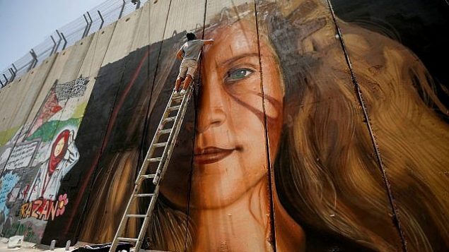 رجل يرسم جدارية لعهد تميمي على الجدار  الامني في مدينة بيت لحم في الضفة الغربية، 25 يوليو 2018 (Wisam Hashlamoun/Flash90)
