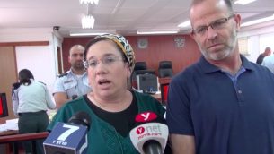 نيريت زامورا تتحدث مع صحفيين داخل محكمة يهودا العسكرية، الى جانب زوجها، قبل محاكمة منفذ هجوم ضدها، 16 يوليو 2018 (Screen capture/Israel National News)