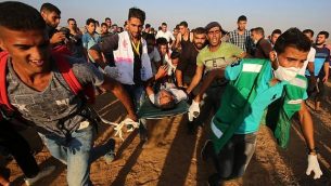 مسعفون فلسطينيون يحملون متظاهر مصاب خلال التظاهرات على الحدود بين إسرائيل وقطاع غزة، شرق خان يونس في جنوب قطاع غزة في 24 أغسطس / آب 2018. (AFP/Said Khatib)