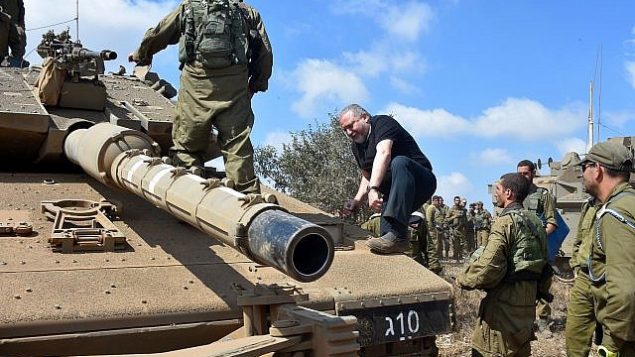 وزير الدفاع أفيغدور ليبرمان يتسلق دبابة في مرتفعات الجولان في 7 أغسطس عام 2018. (Ariel Hermoni/Defense Ministry)