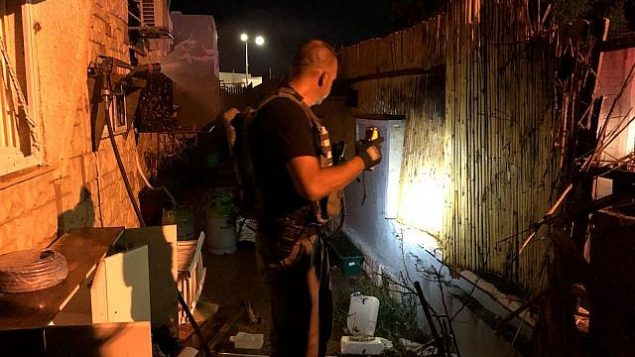 خبراء متفجرات يفتشون ساحة منزل اصيب بصاروخ اطلق من غزة داخل بلدة سديروت في جنود اسرائيل، 8 اغسطس 2018 (Israel Police)