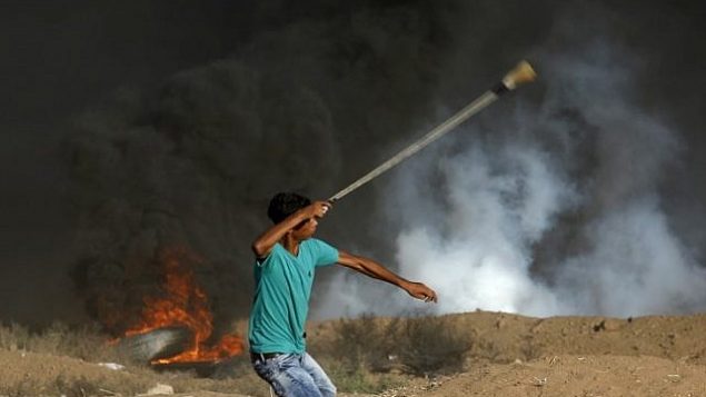 متظاهر فلسطيني يستخدم مقلاعا لإلقاء الحجارة باتجاه القوات الإسرائيلية التي أطلقت الغاز المسيل للدموع خلال مظاهرة على امتداد السياج الحدودي شرق مدينة غزة في 14 سبتمبر 2018. (AFP/Said Khatib)