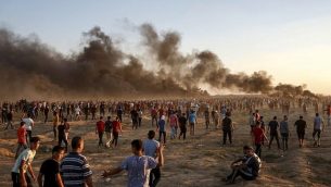 متظاهرون فلسطينيون يجتمعون أثناء مظاهرة على امتداد السياج الحدودي الإسرائيلي شرق مدينة غزة في 21 سبتمبر 2018 حيث تتصاعد أعمدة الدخان من الإطارات المحترقة في الخلفية. (AFP/Said Khatib)